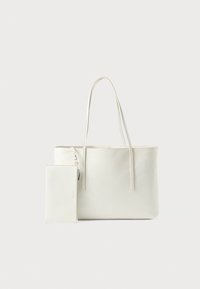 Crème tote bag met lange handvatten en een bijgevoegde kleine bijpassende ritstas op een effen achtergrond.