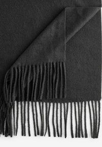 Écharpe en laine gris foncé avec des bords frangés, texture lisse et un coin replié révélant le tissu doux en dessous.