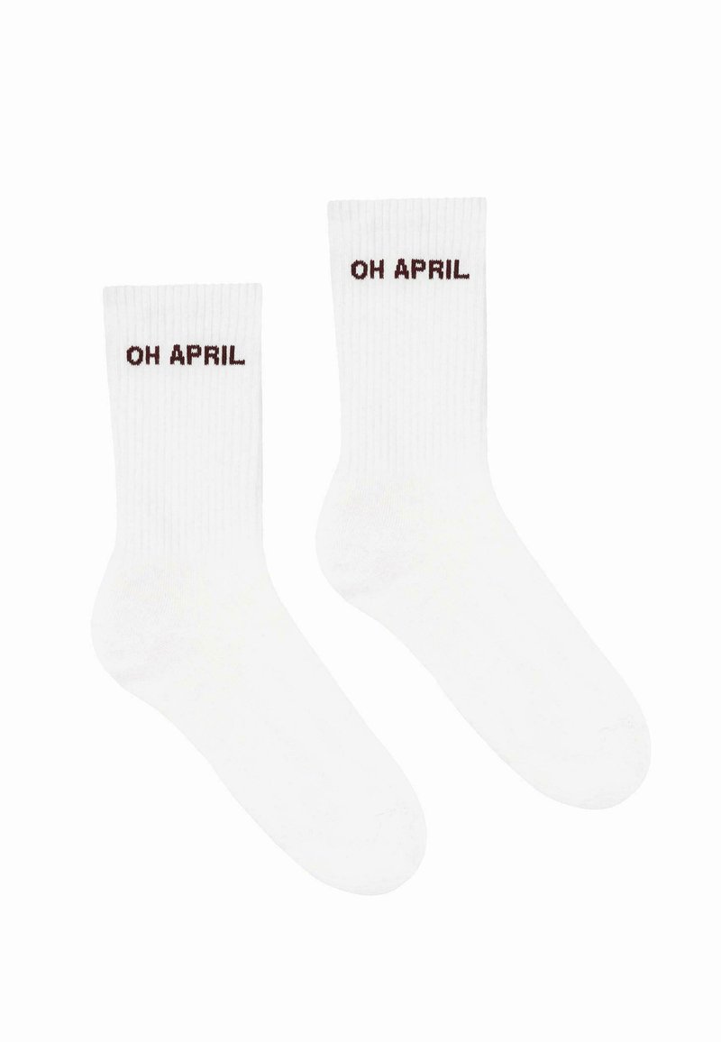 Hvide ribbede sokker med teksten "OH APRIL" i mørkebrunt. Designet har en klassisk form med højde til midten af læggen.