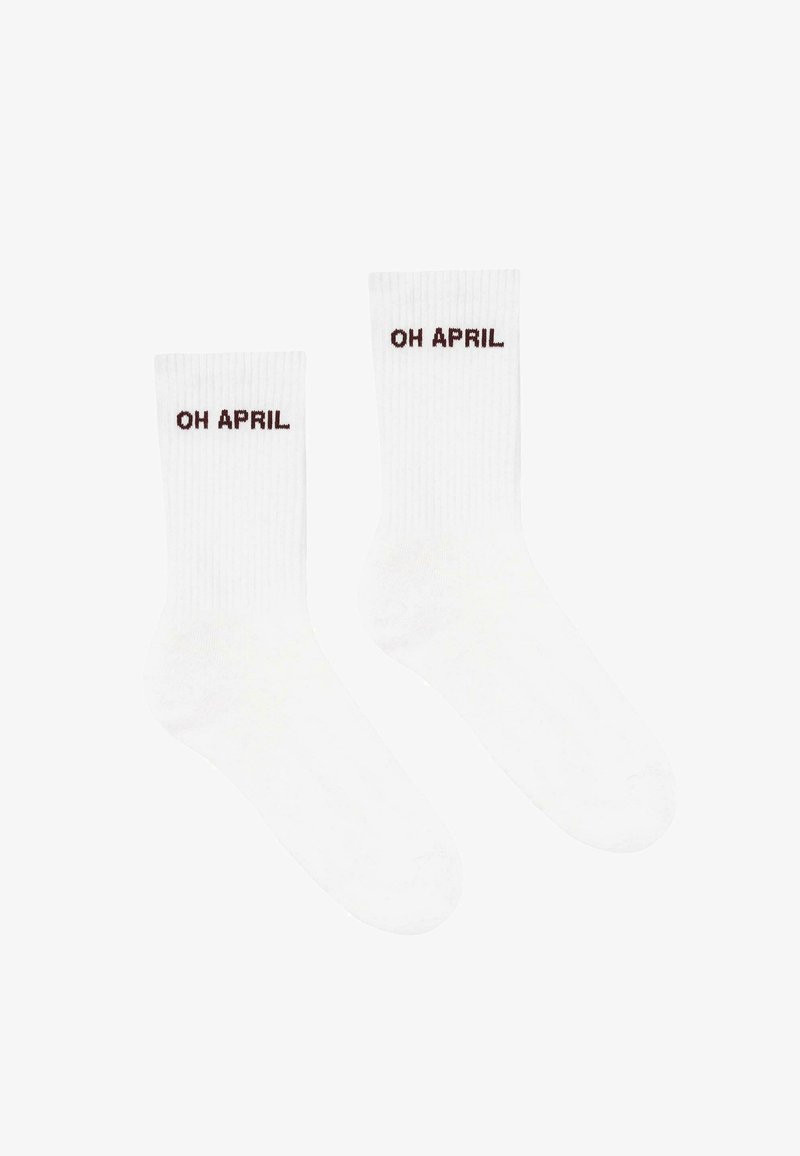 Weiße gerippte Socken mit dem Text "OH APRIL" in Dunkelbraun. Das Design umfasst eine klassische Form mit mittelhohem Schaft.