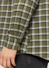 Groen geruite flanellen shirt met witte en zwarte vierkantpatronen, voorzien van een bordeaux knoopsluiting en een klein logo-etiket. Zachte stoffen textuur.