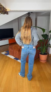 Sweatshirt cinzento e jeans de ganga azul vistos de trás. Textura lisa, design de perna reta, jeans de lavagem média e bolsos traseiros minimalistas.