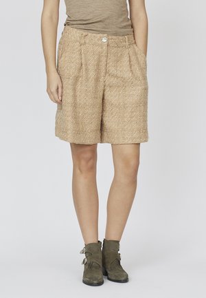 Beige teksturerede shorts lavet af vævet stof, med en frontknaplukning og sidelommer, parret med olivenfarvede ankelstøvler.