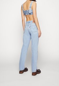 Ljusblå denimjeans med rak passform, hög midja och bakfickor. Matchas med en kort topp med justerbara remmar.