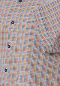 Korte mouwen shirt met een bontgekleurde ruitpatroon in blauwe, rode en gele tinten, knoopsluitingen en een zak op de linkerborst.