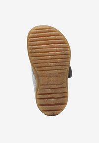 Buty na gumowej podeszwie z teksturowanym brązowym spodem, z poziomymi rowkami i jasnym, puszystym u góry, z widocznym logo marki.