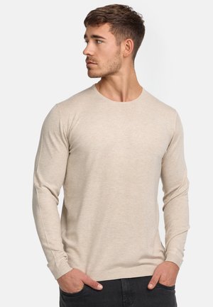 Camisa de manga larga beige con cuello redondo, de ajuste slim, hecha de un tejido de punto texturizado, con puños y dobladillo de canalé.