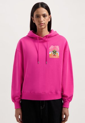 Fuchsia hoodie with a drawstring hood, ribbed cuffs, and a graphic patch featuring a cartoon design on the left chest area.