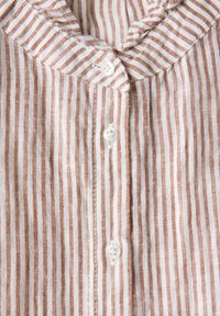 Camicia a righe bianca e terracotta, con colletto rotondo, chiusura con bottoni e tessuto leggero e textured. Linee verticali distintive.