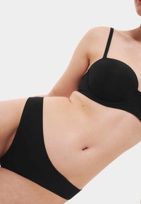 Czarny zestaw bikini z formowanym stanikiem na cienkich ramiączkach i pasującymi majtkami w wysokim stanie; gładki materiał z minimalnymi detalami.