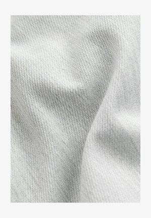 Lichtgrijze stof met een zachte, iets gestructureerde oppervlakte en een subtiel ribbelpatroon, waarin plooien en kreuken zichtbaar zijn in de val.