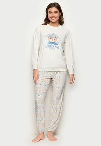 Langærmet cremefarvet pyjamastop med grafik "APRES SKI LOVER" og bjørn, kombineret med lyse mønstrede bukser med drikkevarer og snefnug.