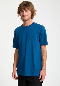 Kurzarm-T-Shirt mit Rundhalsausschnitt aus leuchtend blauem Baumwollstoff, mit kleinem schwarzem Logo auf der Brust und lockerer Passform.