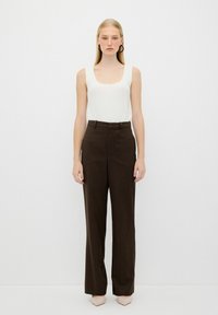 Vit ribbad ärmkanal med bruna randiga högmidjade byxor. Outfitten har en skräddarsydd design och rak ben silhuett.