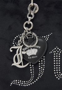 Silver Juicy Couture pendant and heart-shaped black leather tag with crown and "The Queen" text on black fabric with rhinestones.