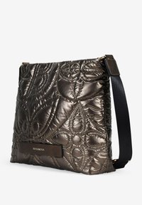 Bolso de bronce metálico acolchado con una superficie texturizada, que presenta intrincados patrones de costura, un parche de cuero oscuro con el logo y una correa adjustable.
