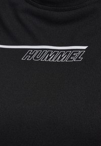 Svart träningsskjorta med ribbad textur, med vit "HUMMEL"-logotyp och horisontell vit rand.