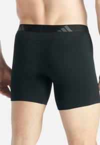 Zwarte boxershorts met een soepele textuur, elastische tailleband met grijze accenten en een aansluitend ontwerp, dat zorgt voor bedekking en ondersteuning.
