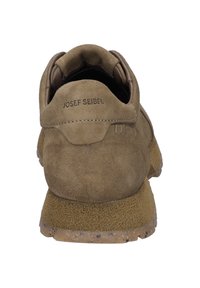 Brun mockaskor med mjuk textur, rund bakdel och gummisula. Har logotext på hälen och dekorativa sömmar.