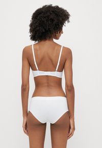 Biały zestaw biustonosza i majtek, z regulowanymi ramiączkami, gładką fakturą i prostym wzornictwem. Zapięcie z tyłu z minimalistycznym pasem.