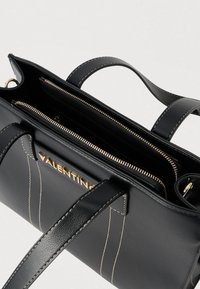 Fekete bőrből készült női táska aranyszínű fém kiegészítőkkel, több rekesszel, felső fogantyúkkal és kontrasztos varrási részletekkel.