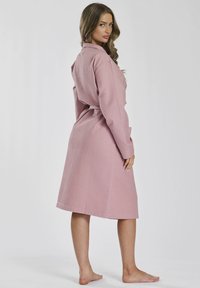 Accappatoio rosa con texture, vita con cintura, maniche lunghe, taglio al ginocchio e motivo a scacchi. Presenta tasche e una vestibilità relax.