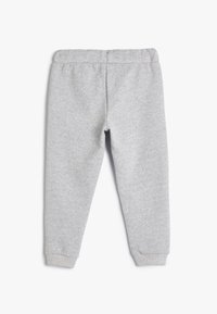 Pantalones de chándal grises con cintura y puños elásticos. La tela tiene una textura suave y un acabado liso. Diseñados para comodidad y uso casual.