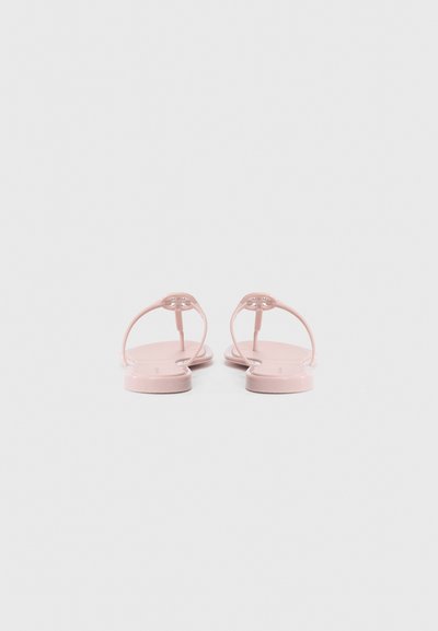 Sandales en caoutchouc rose avec de fines bandes et une semelle plate. Présente un détail de boucle décoratif au niveau du talon. Texture lisse, design minimaliste.