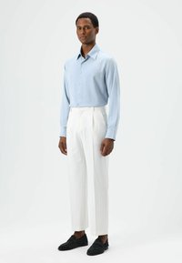 Light blue long-sleeve shirt, white pleated trousers, and black suede loafers. Smooth fabric, tailored fit, and classic collar design.