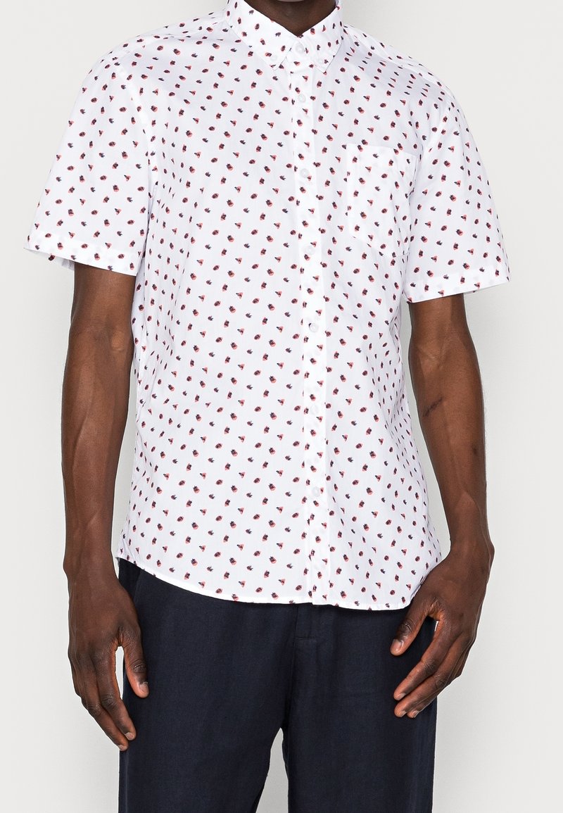 Chemise à manches courtes à boutons en tissu blanc avec un petit motif floral rouge. Comprend une poche poitrine et un col standard.