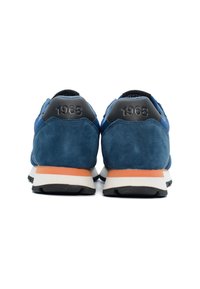 Blaue Wildleder-Sneaker mit schwarzen Fersenakzenten, ausgestattet mit einer weißen Zwischensohle und orangefarbenen Details. Das Jahr "1968" ist auf der Ferse geprägt.