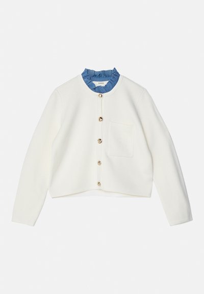 Cardigan alb tricotat cu un guler albastru cu volane, având un buzunar frontal și butoane aurii pe deschidere. Lungime scurtă, cu mâneci lungi.