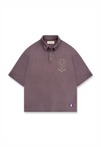 Polo mauve à manches courtes avec col, emblème sur la poitrine indiquant "Atelier Reternity", et petit patch du drapeau français près de l'ourlet.