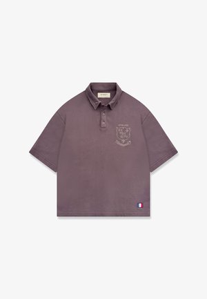 Polo mauve à manches courtes avec col, emblème sur la poitrine indiquant "Atelier Reternity", et petit patch du drapeau français près de l'ourlet.