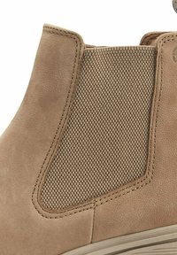 Bottine en cuir marron avec un panneau latéral en élastique tissé et des coutures contrastantes, doté d'une texture lisse et d'une forme arrondie.