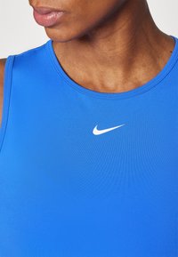 Blauw sportief tanktopje gemaakt van glad, rekbaar stof. Heeft een ronde halslijn en een klein wit Nike-logo op de borst.