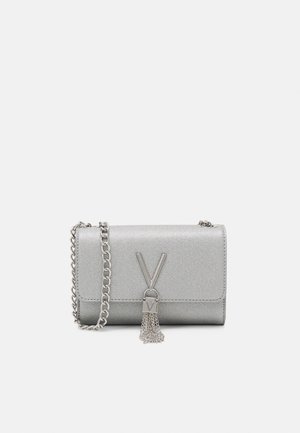 Petit sac à main argenté avec bandoulière chaîne et fermoir décoratif en métal en forme de V avec pampille en chaîne à l'avant.