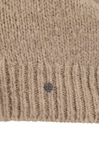 Berretto lavorato a maglia beige con texture a costine. Presenta un piccolo tag metallico con la scritta "by Lingo", posizionato vicino al bordo inferiore.