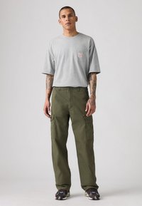 Gray cotton t-shirt with a small label on the chest, paired with olive green cargo pants featuring side pockets and a loose fit.