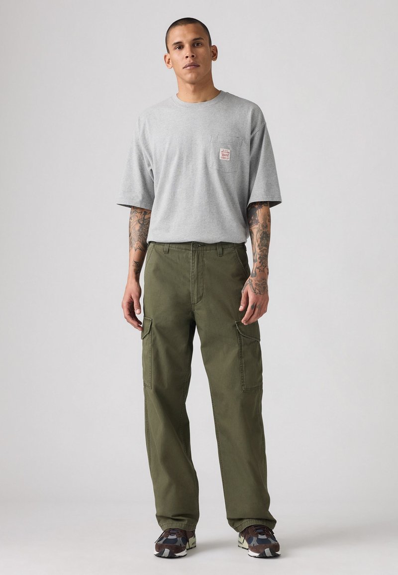 Gray cotton t-shirt with a small label on the chest, paired with olive green cargo pants featuring side pockets and a loose fit.
