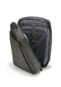 Sac à dos gris fabriqué en matériau durable, avec un compartiment principal zippé, des poches internes et une forme structurée pour l'organisation.