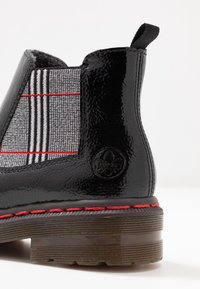 Svart lackläder ankelboot med ett rutigt textilpanel som har röda detaljer. Tjock sula med synlig sömnad och logotypdetalj.