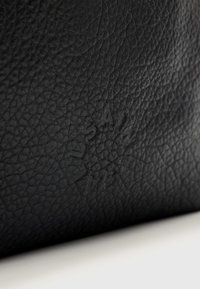 Zwarte leren tas met een gestructureerd oppervlak. Heeft een reliëfmerk aan één zijde, waarmee het materiaal en het ontwerp worden benadrukt.