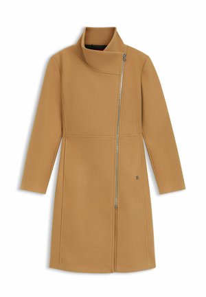 Lang jas in kameelkleur met asymmetrische zilveren ritssluiting die loopt van de kraag naar de rechterbenedenkant, voorzien van een hoge, opgevouwen kraag.