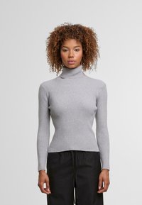 Szary sweter z golfem z prążkowanej tkaniny, z długimi rękawami, dopasowany kroj i miękka tekstura. Noszony z regulowanymi czarnymi spodniami.