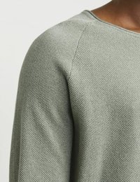 Helle grüne Strickjacke mit strukturiertem Muster, ausgestattet mit einem Rundhalskragen und Raglanärmeln. Der Stoff wirkt weich und atmungsaktiv.