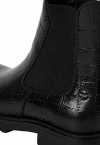 Musta nahkainen Chelsea-saapas, jossa on teksturoitu krokotiilikuosi ja joustava sivupaneli. Kestävä kumipohja ja sävy sävyyn ompeluyksityiskohdat.