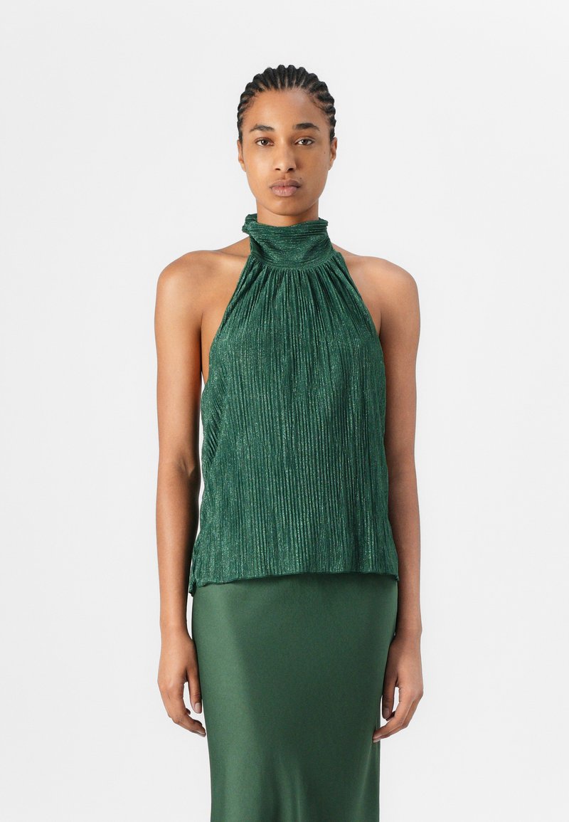 Top halter plissettato verde realizzato in un tessuto lucido e testurizzato. Presenta un collo alto con arricciature all'altezza del collo. Abbinato a una gonna verde.