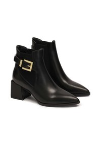 Black leather ankle boots with pointed toes, elastic side panels, and a gold buckle accent on a chunky block heel. Textured fabric insets.