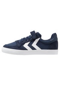 Navy blue canvas sneakers with white accents, round toe, lace-up design, and a hook-and-loop strap for added security. Flat rubber sole.
